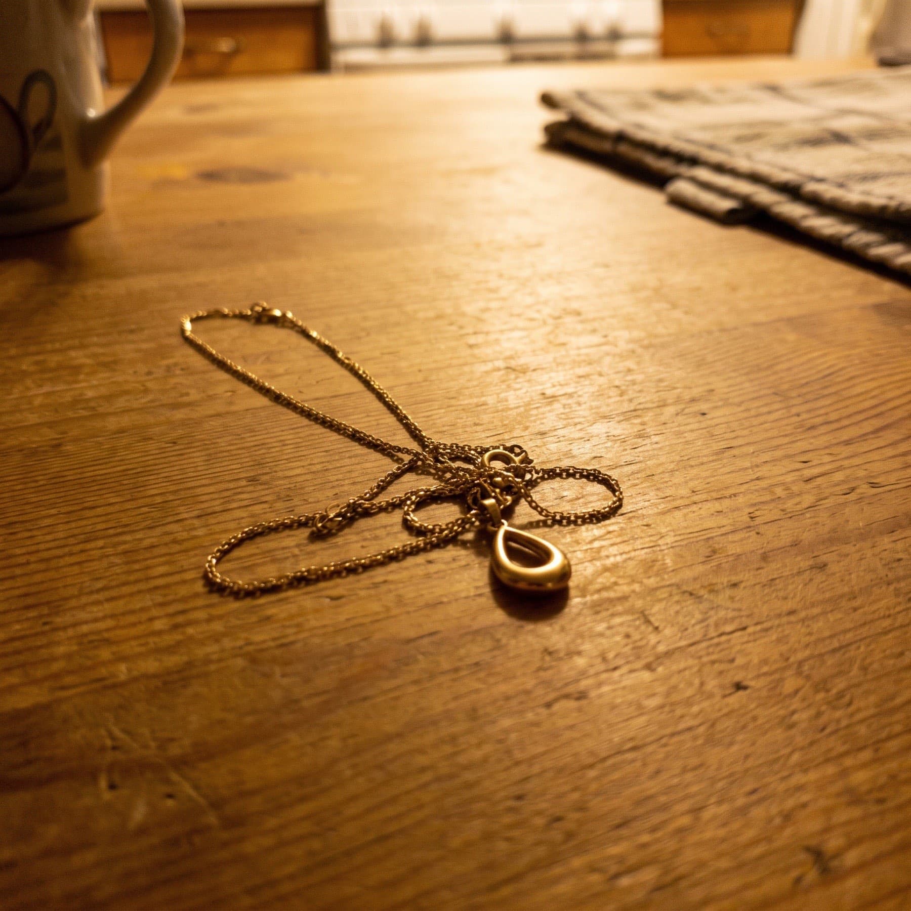 A necklace shot on a table with a phone, and the same piece as a clean product shot
