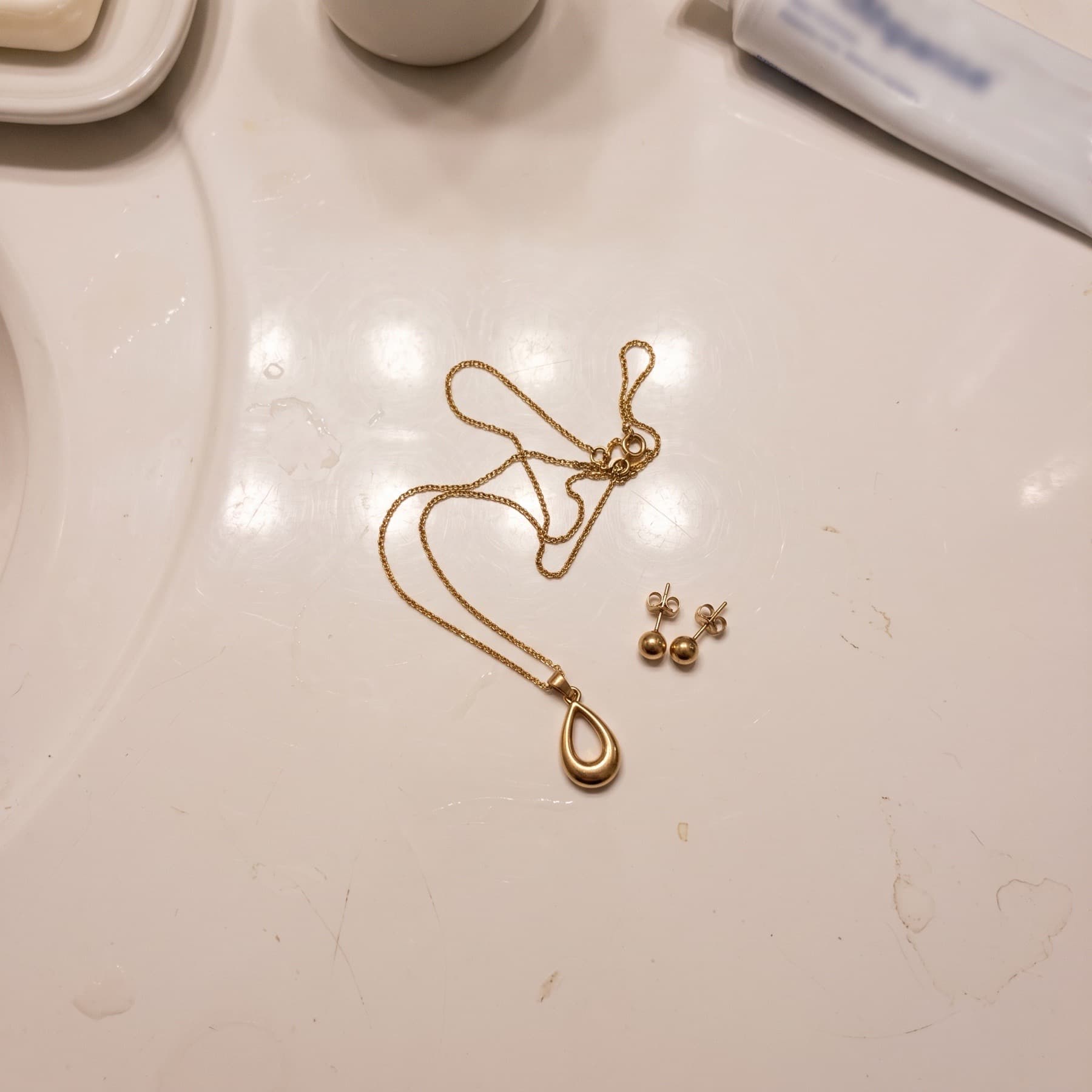 A necklace lying on a bathroom counter, and the same necklace worn by a model